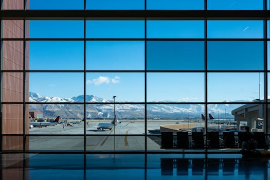 Panoramic view of airport terminal and runway with snow-capped mountains in the background.