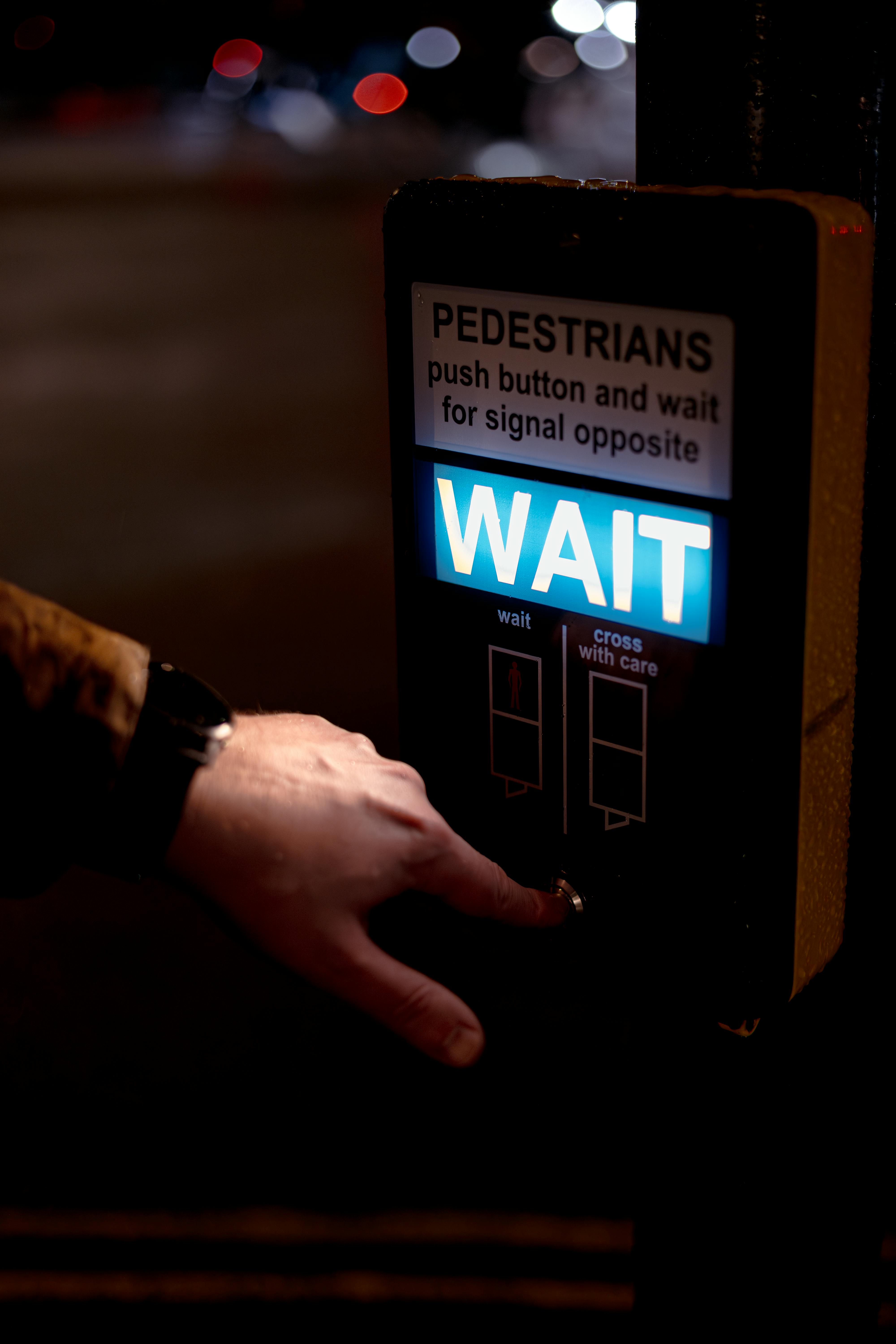 Close-up of a hand pressing a crosswalk button at night in London, England.