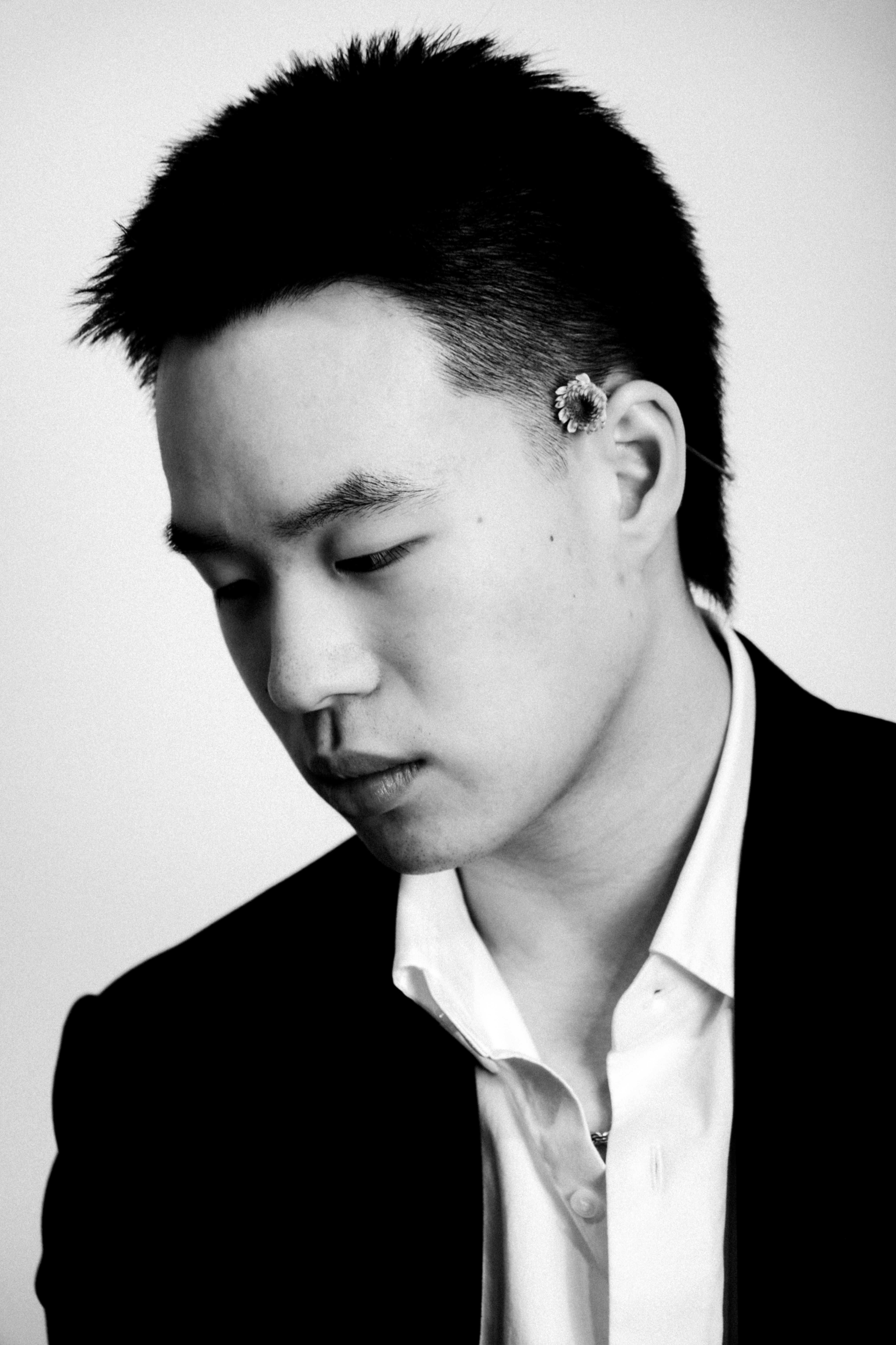 Monochrome studio portrait of a man in a suit with floral accent. Elegant and artistic vibe.