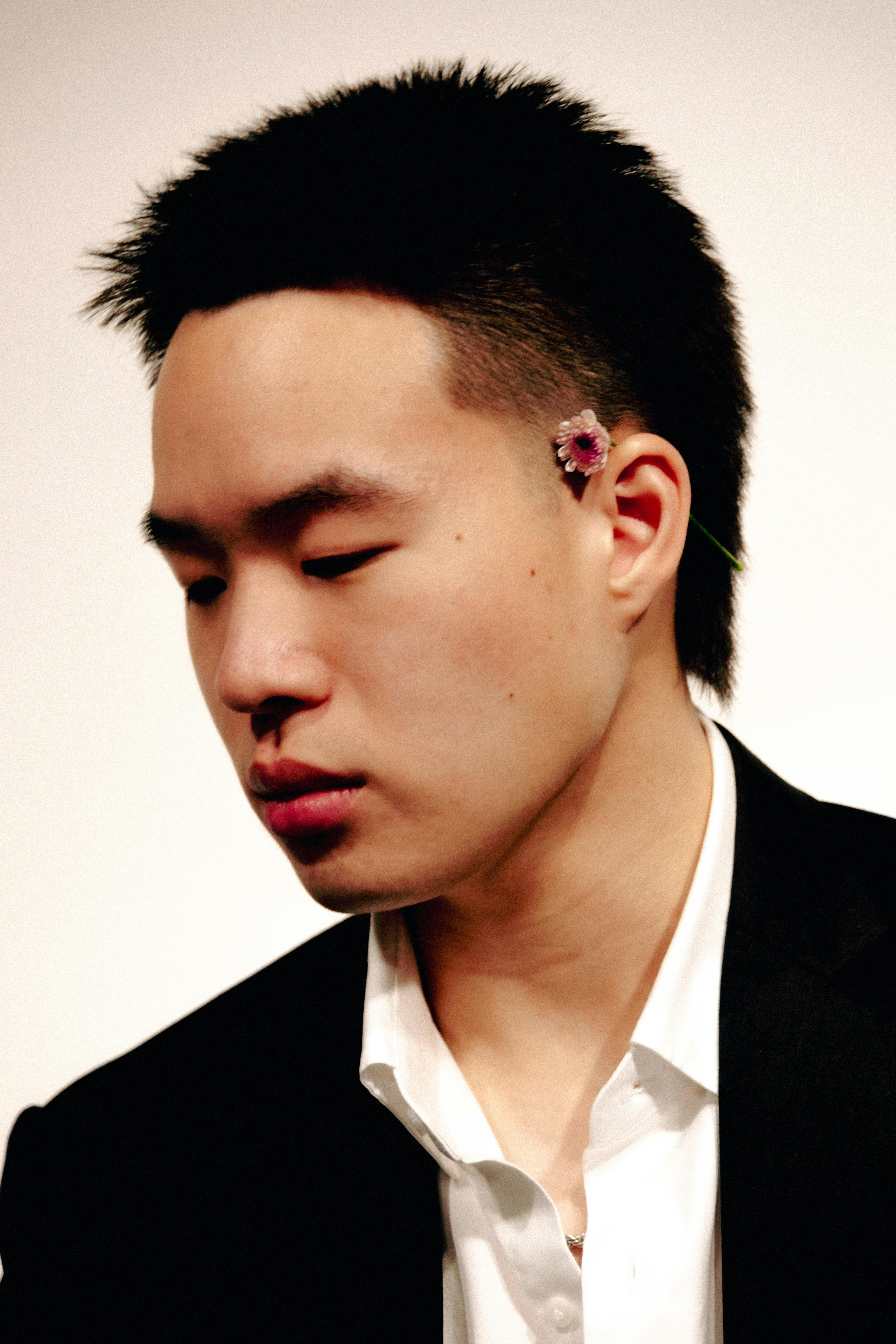 Elegant studio portrait of a man wearing a suit with a flower accessory, exuding creativity.