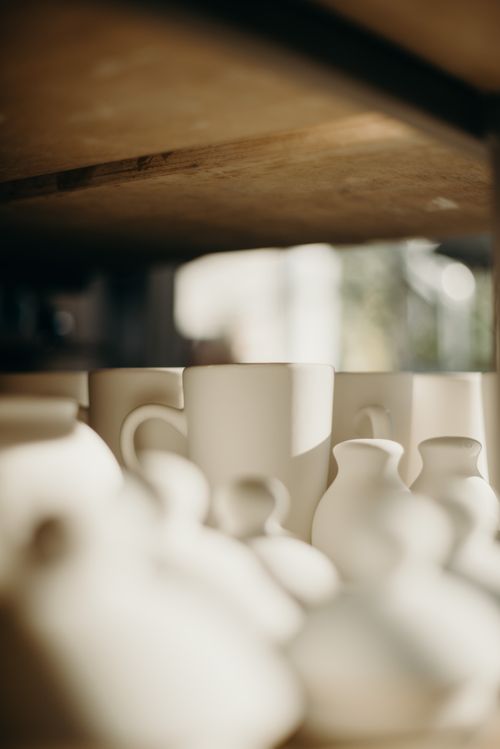 Free A selection of handmade ceramic pottery and mugs displayed on a wooden shelf. Stock Photo