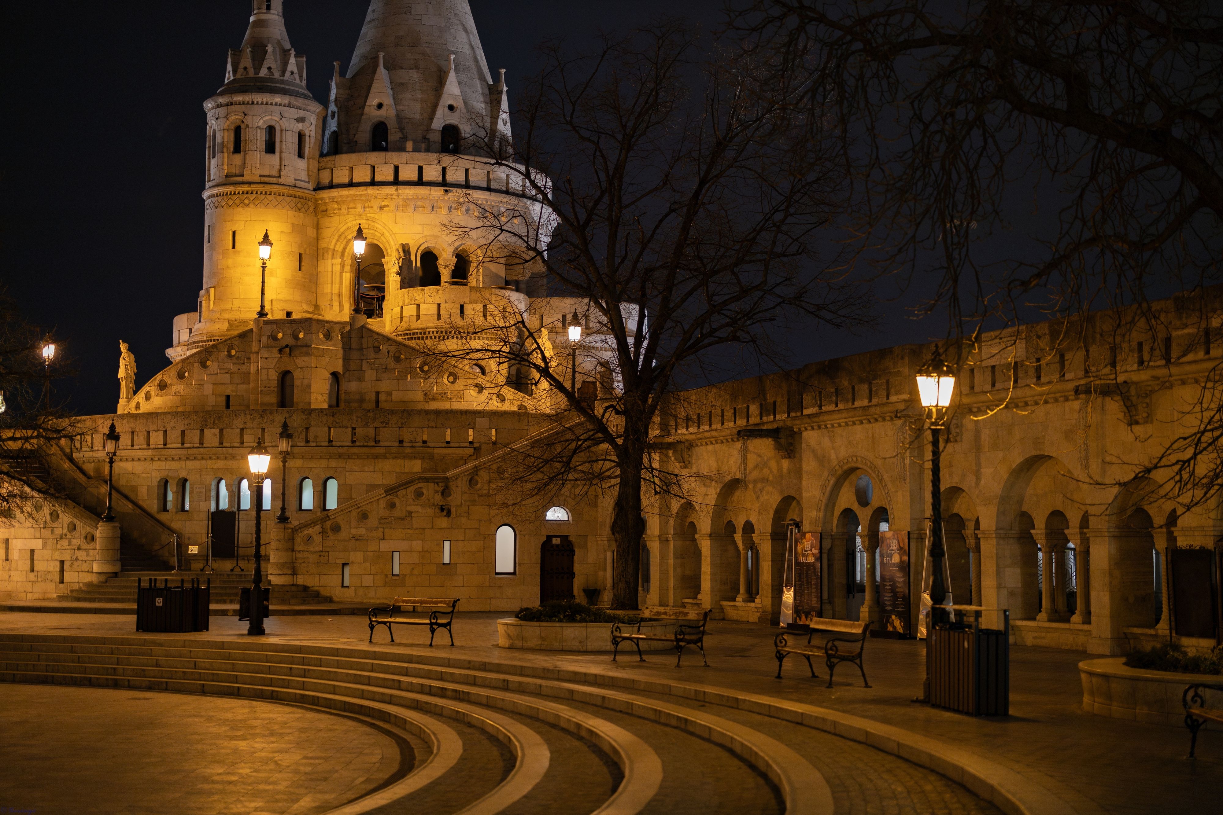 Fotomural El Bastión de los Pescadores iluminado por la noche en Budapest, mostrando la arquitectura gótica bajo las farolas.