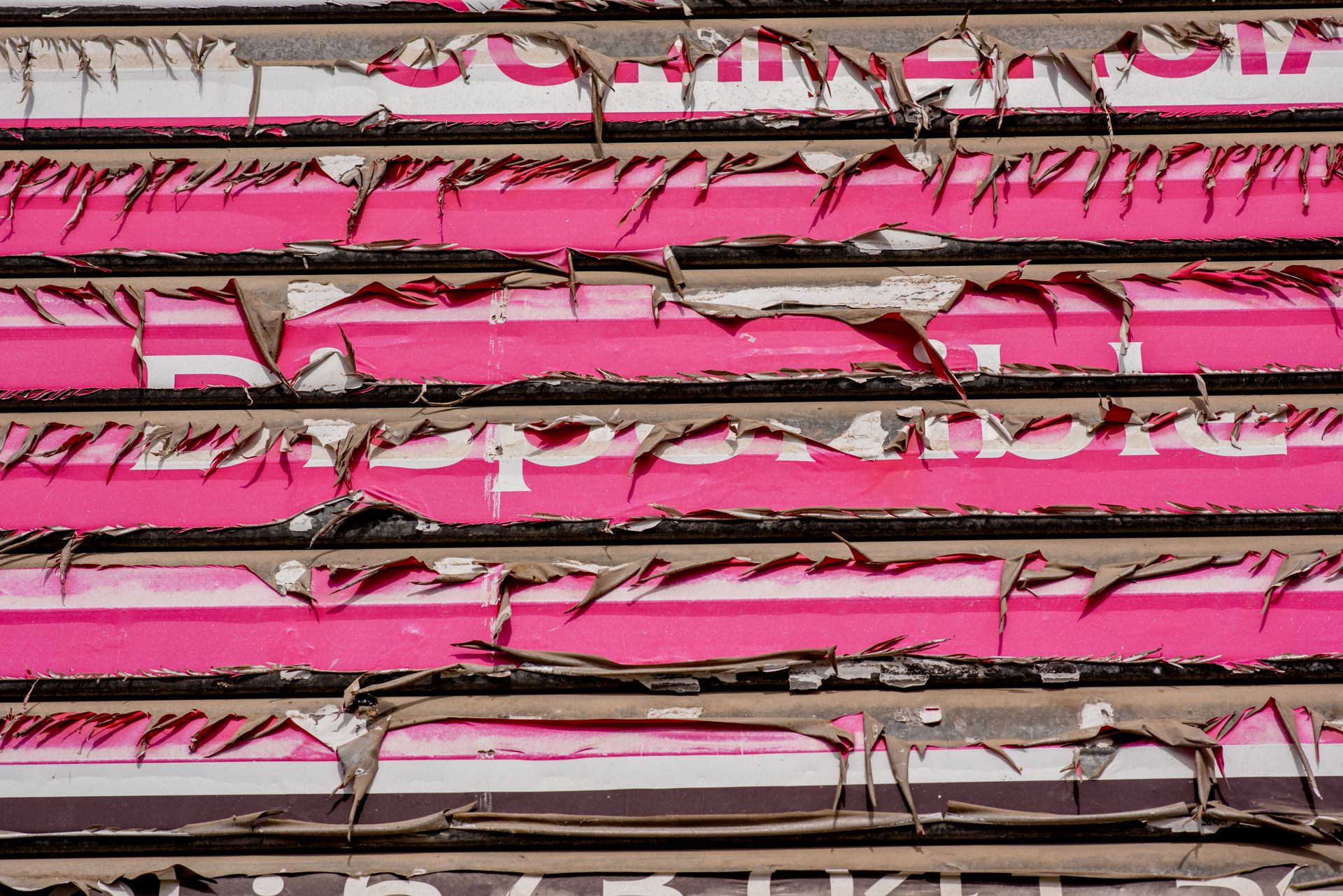 Close-up of peeling billboard revealing layers of bold colors and textures.