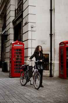 Urban lifestyle in London featuring a stylish person with a bicycle by red phone booths.