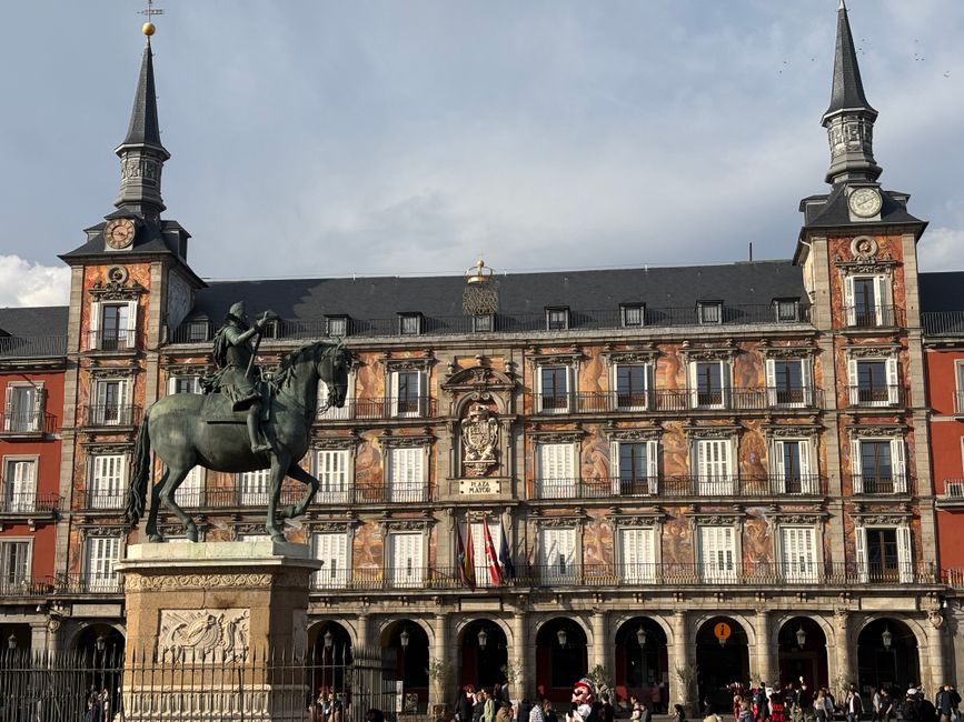 Vista de la Plaza Mayor de Madrid con una estatua ecuestre histórica bajo un cielo brillante.