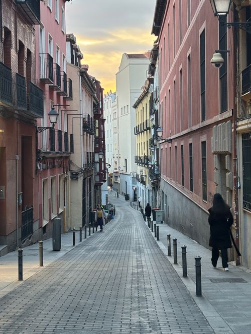 Free A serene street in Madrid captures the city's charming architecture under a colorful sunset sky. Stock Photo