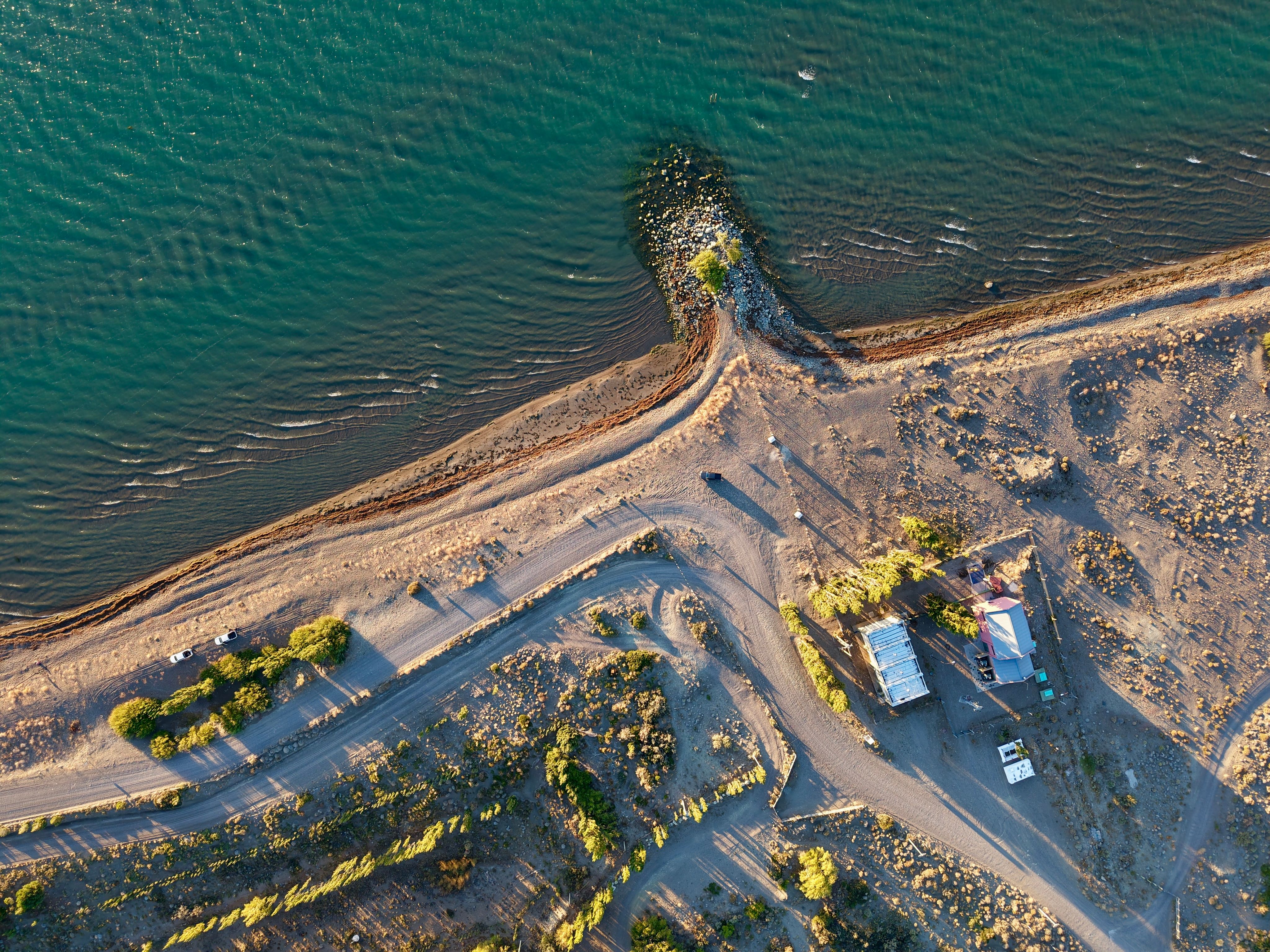 Aerial shot of a deserted lakeside in Chubut, Argentina, showing the shoreline and dirt roads.