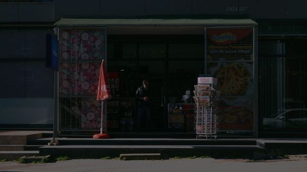 Entrance to a dark small urban convenience store with outdoor displays and signage.