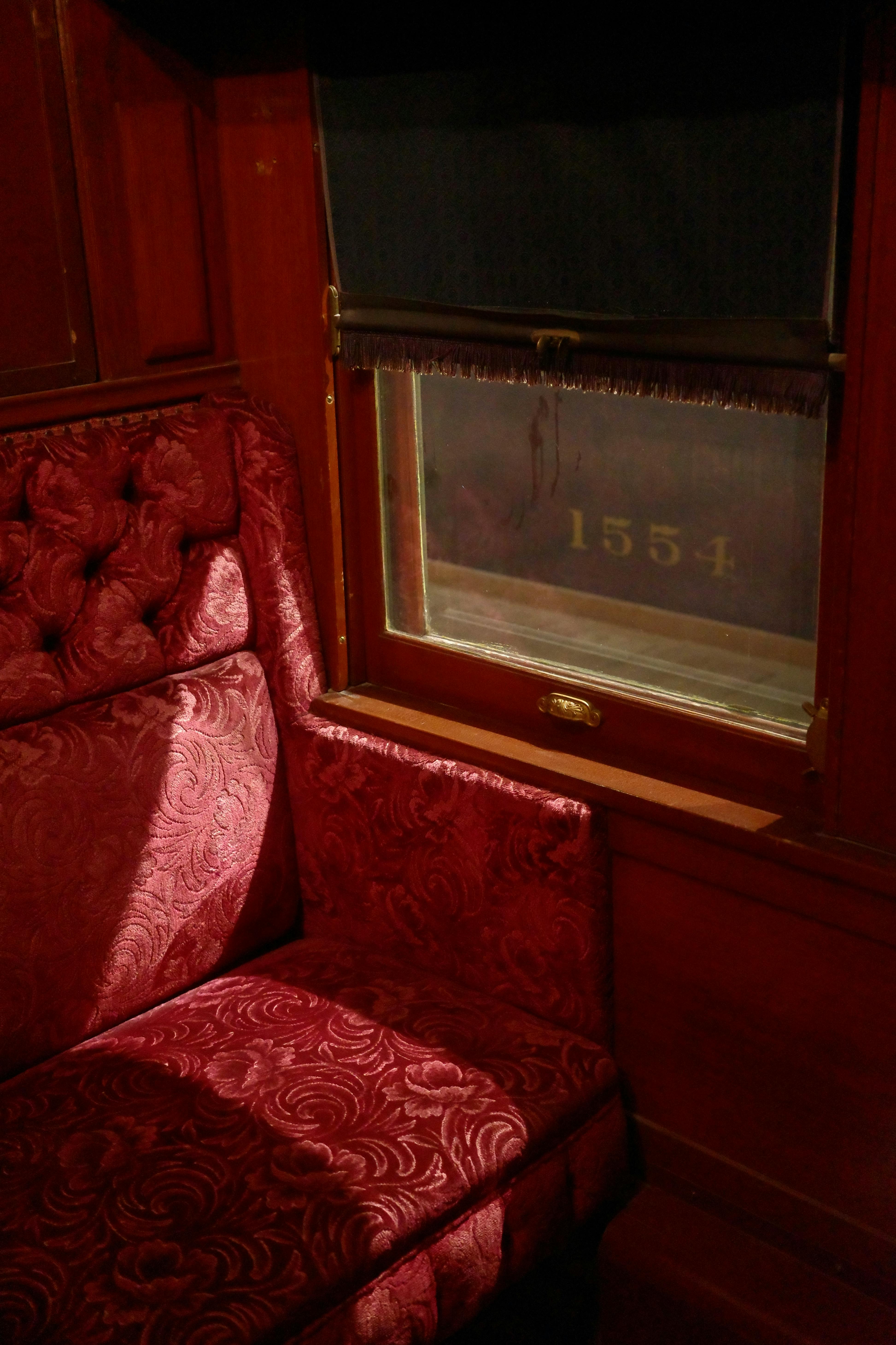 Interior of a vintage train car showcasing ornate upholstery and window details.