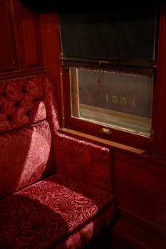 Interior of a vintage train car showcasing ornate upholstery and window details.