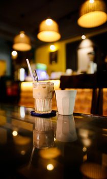 Iced coffee on a table in a warmly lit cafe, perfect for a relaxing atmosphere.