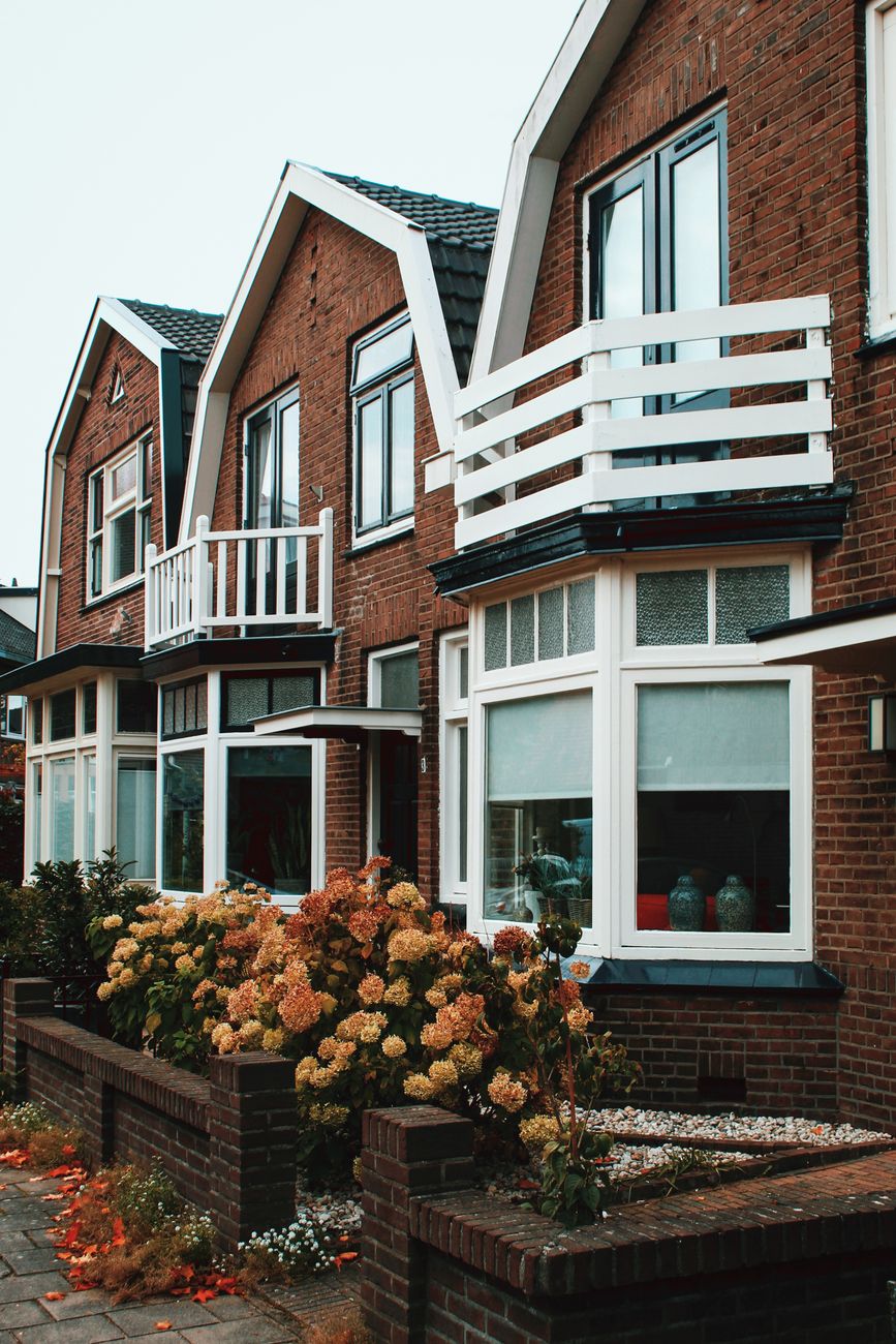 Charmante bakstenen huizen in Deventer met witte balkons en bloeiende bloemen.