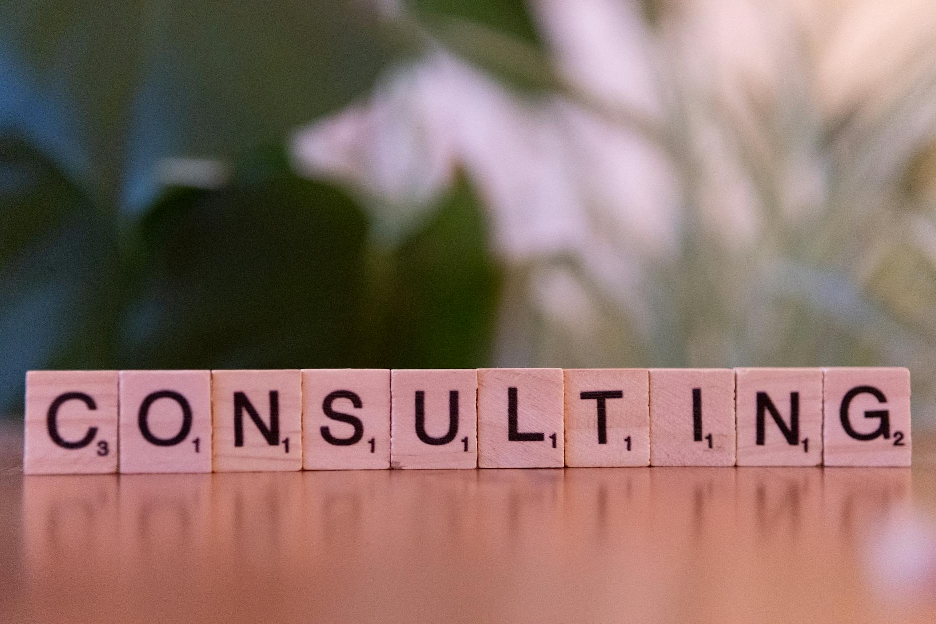 Wooden letter tiles spelling 'Consulting' with a blurred background. Ideal for business concepts.