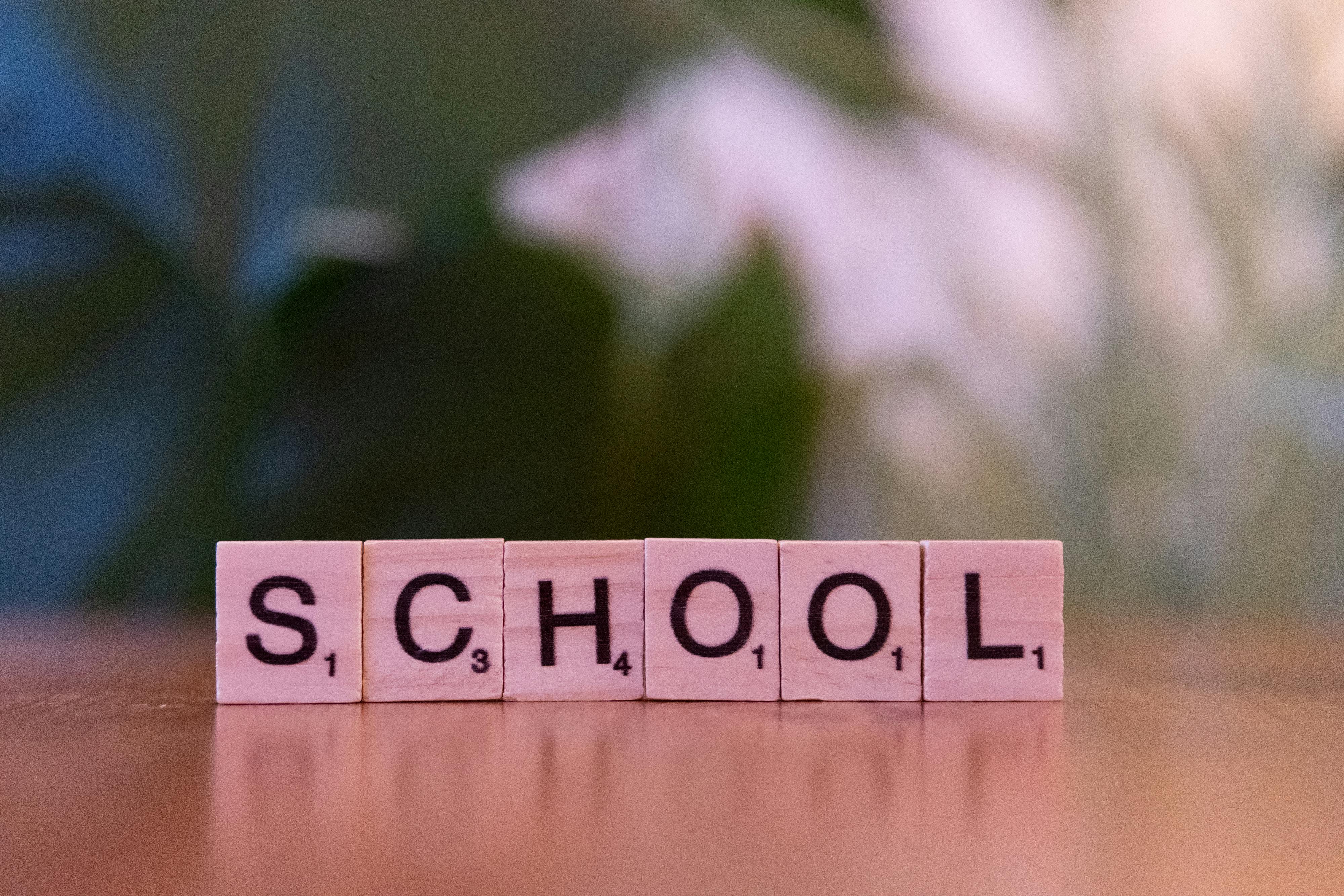 Wooden tiles spelling the word school on a table, evoking educational themes.