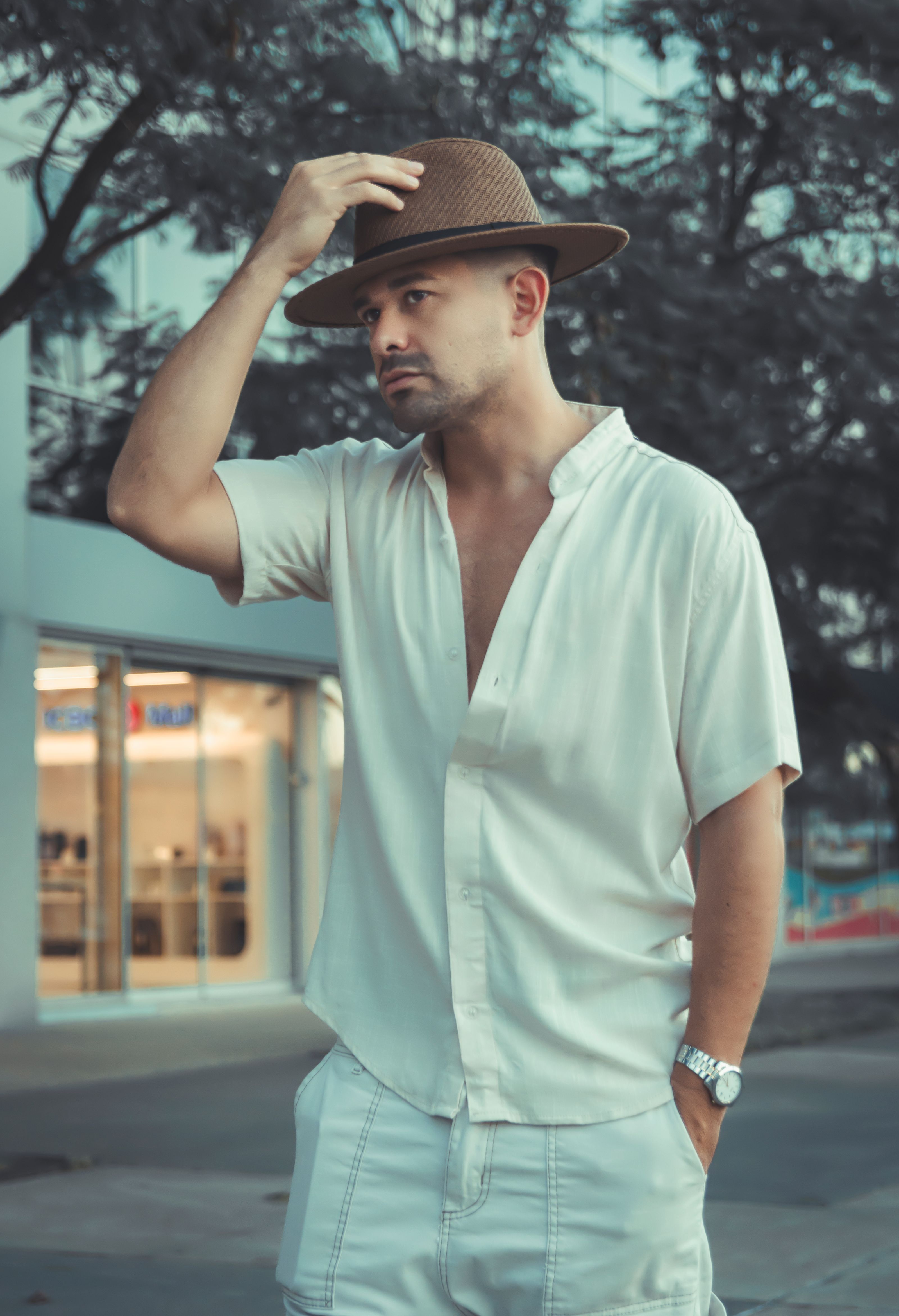 Um homem fashion com um traje casual de verão e chapéu de palha em pé ao ar livre.