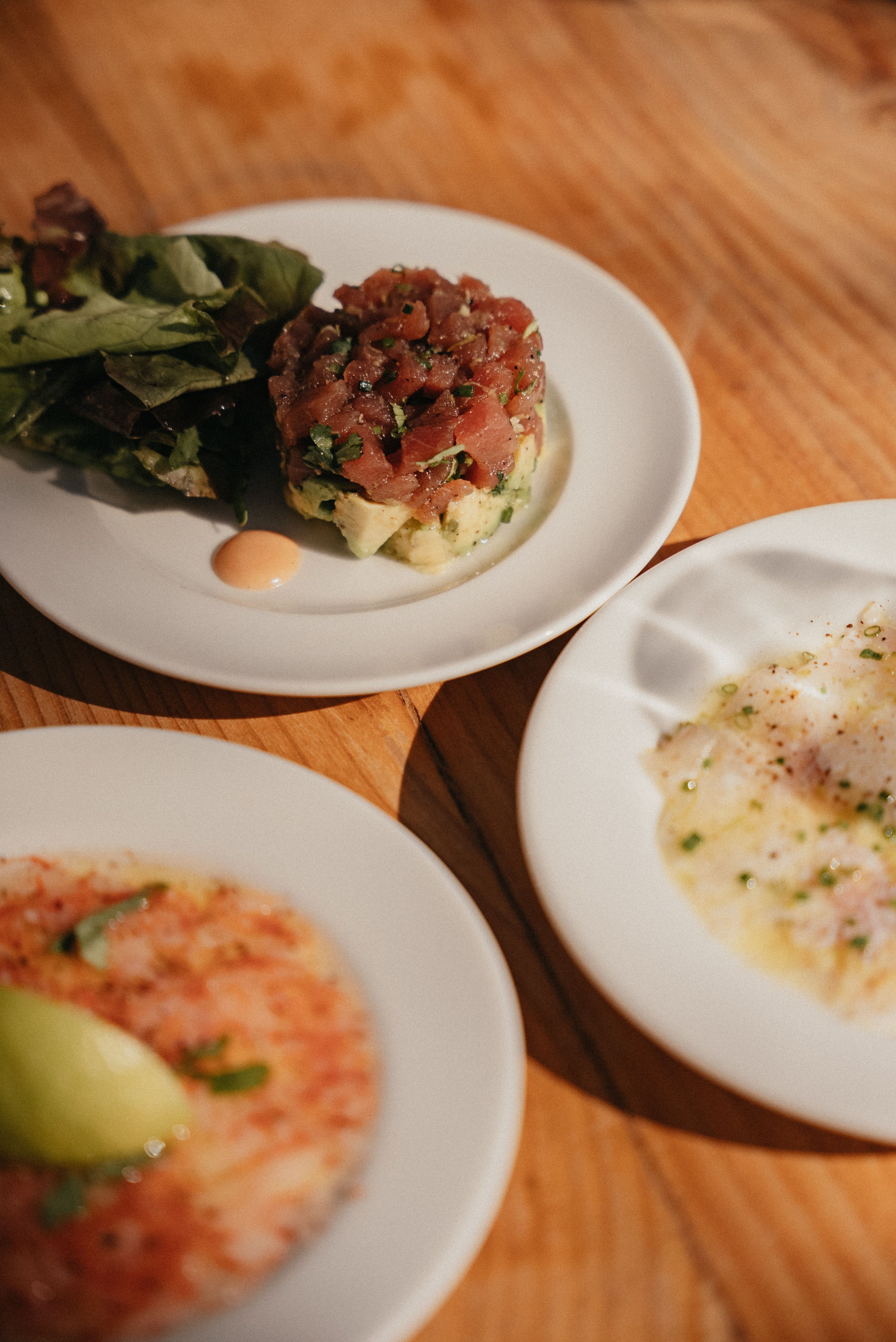 Plates of Moroccan tuna tartare and appetizers elegantly arranged on a wooden table.