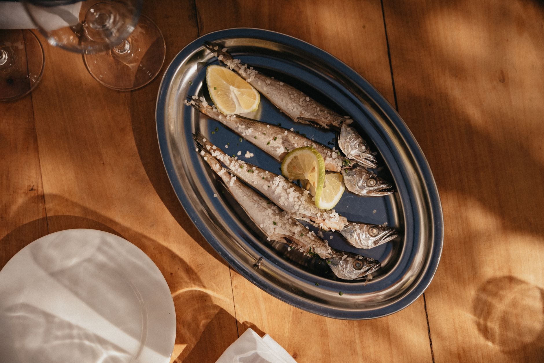 Grilled whole fish and salad on a quayside taverna table beside fishing boats