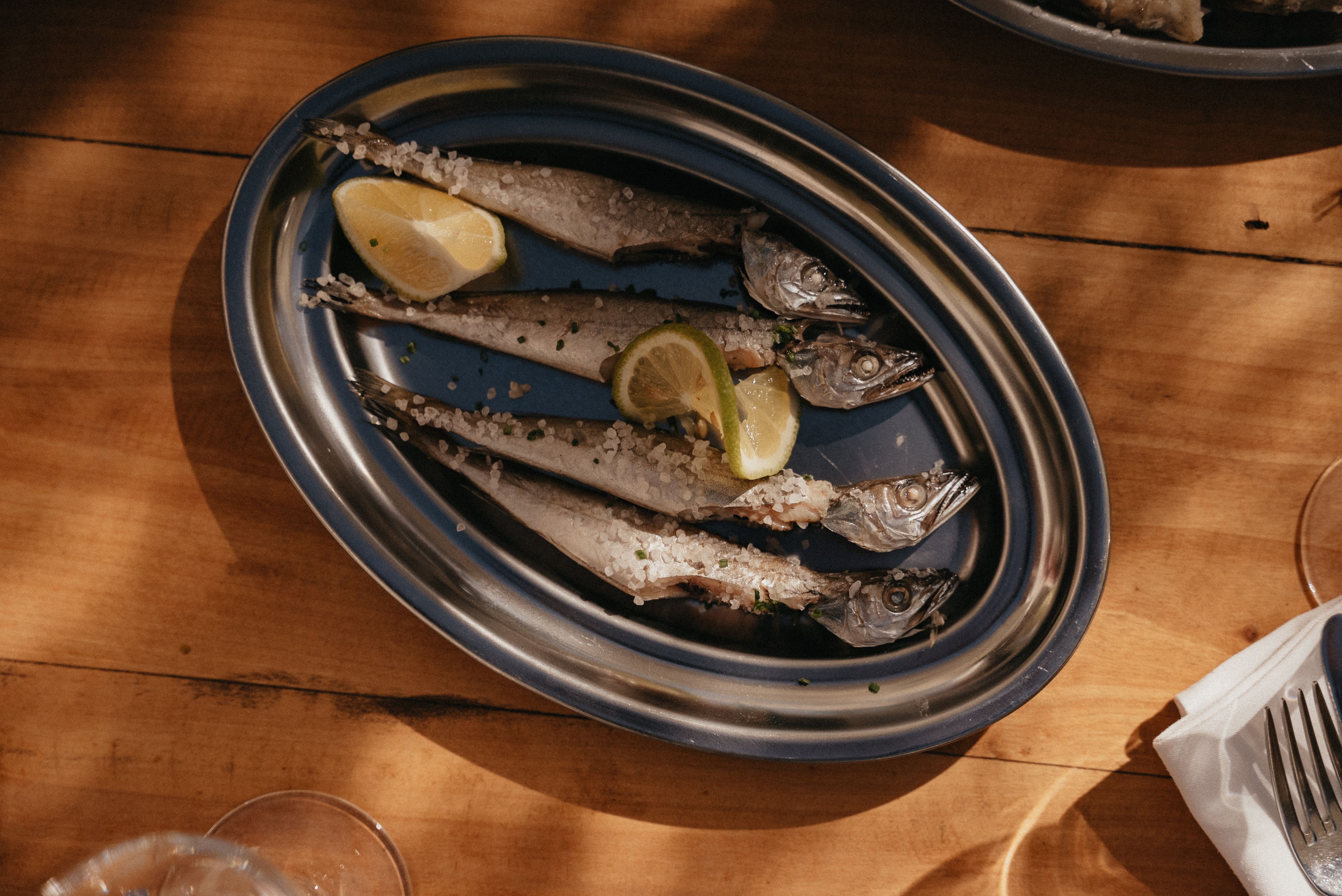 Whole fish on white plate centered on formal dinner table setting