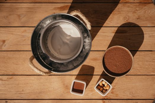 Flat lay of ice cream making ingredients on a wooden surface, captured in natural light.