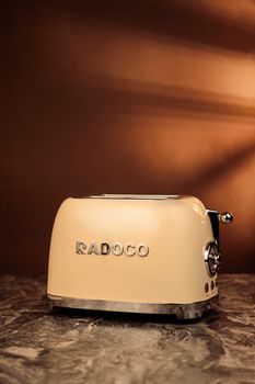 Vintage cream toaster on marble with warm lighting and brown background.