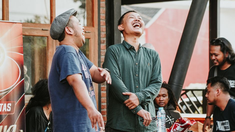 A joyful group of friends laughing and socializing outdoors in East Java, Indonesia.