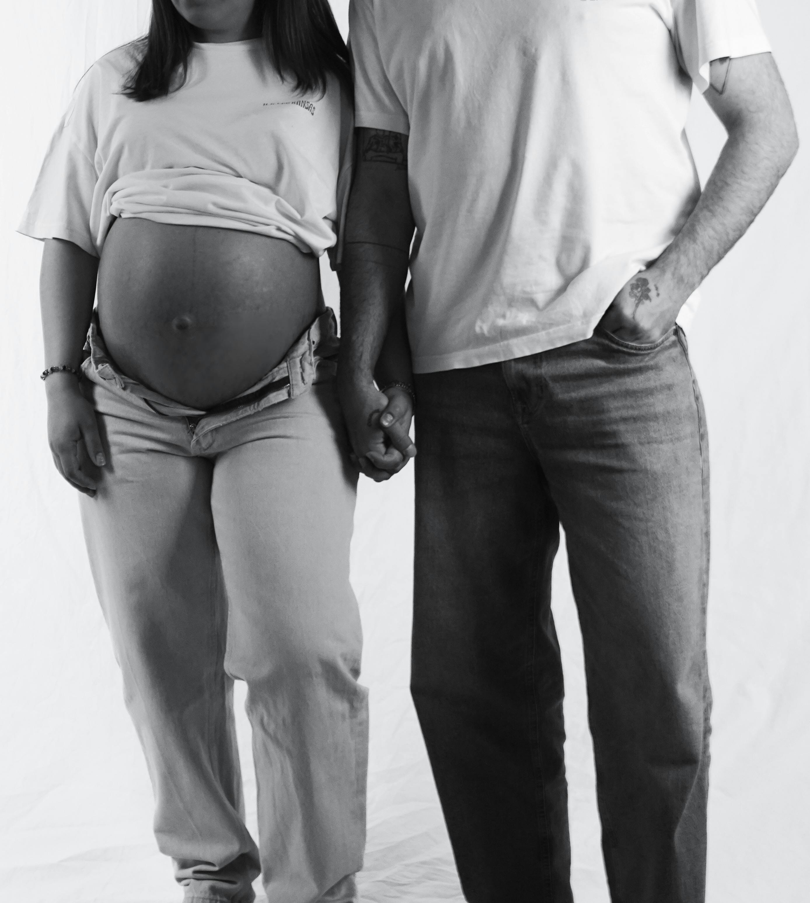 expecting couple holding hands in black and white