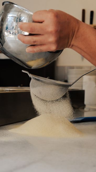 Close-up of hand sifting flour in a kitchen, creating a fine powdery cascade. - home gadgets for small spaces