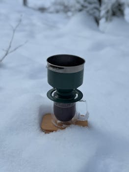 A coffee dripper set on a snow-covered surface during winter.