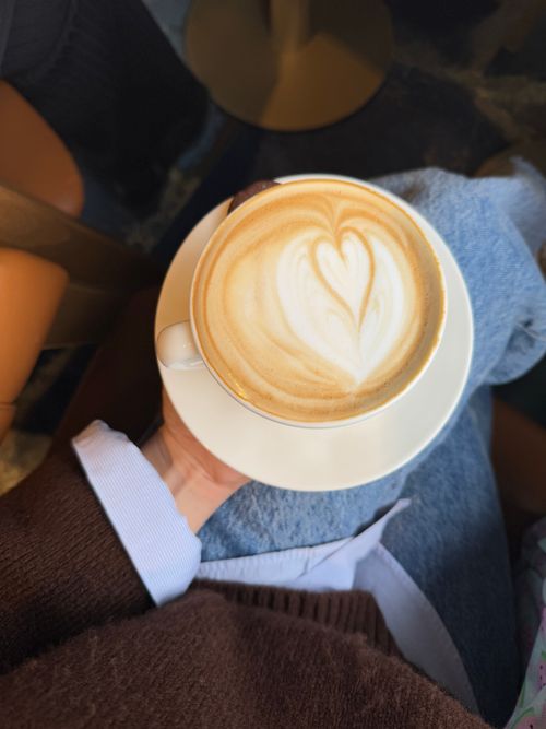 Free Cozy latte in a café with heart-shaped foam art on top. Stock Photo
