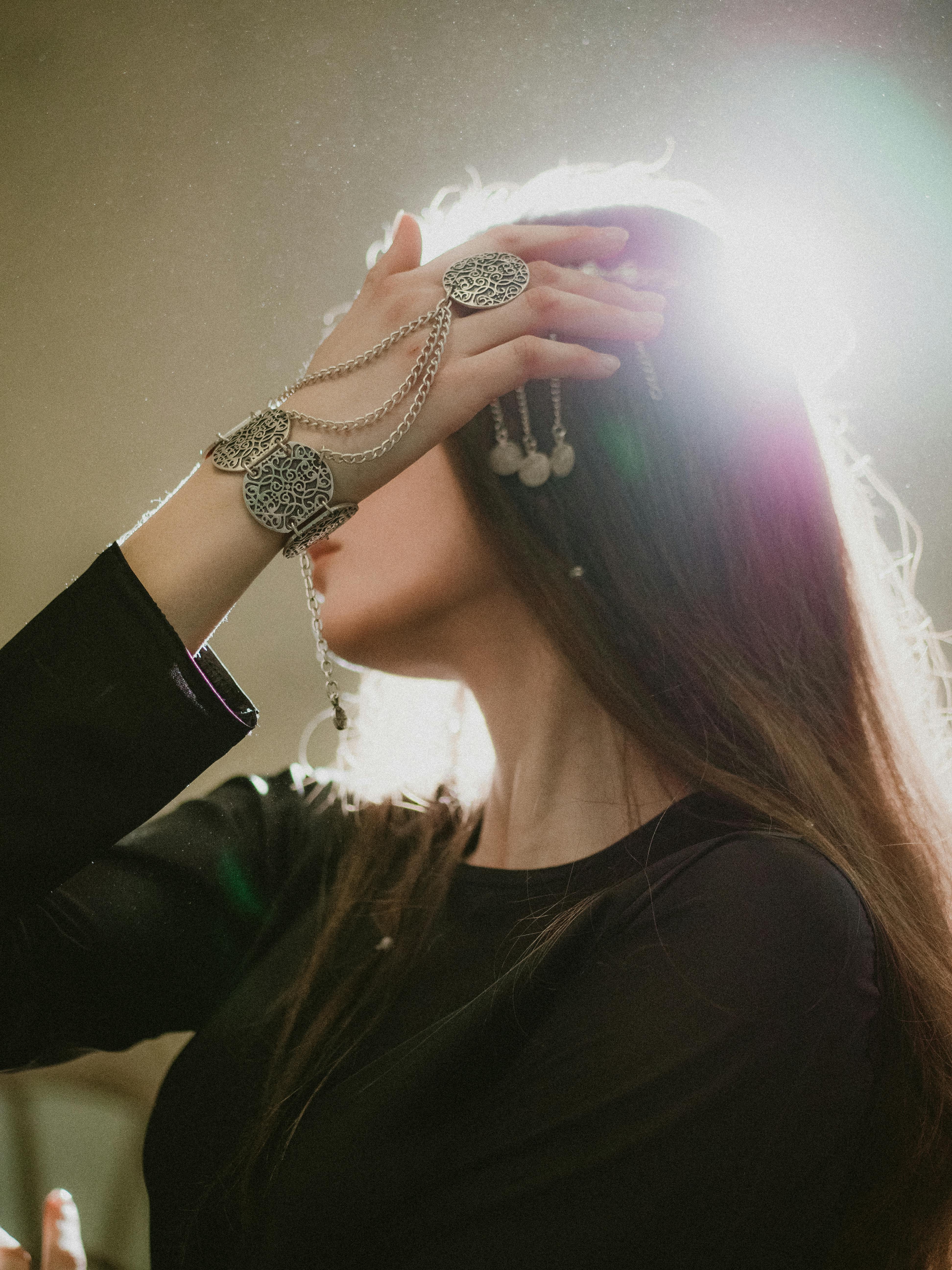 Dramatic side-lit photo of a woman adorned in ornate silver jewelry, creating an ethereal mood.