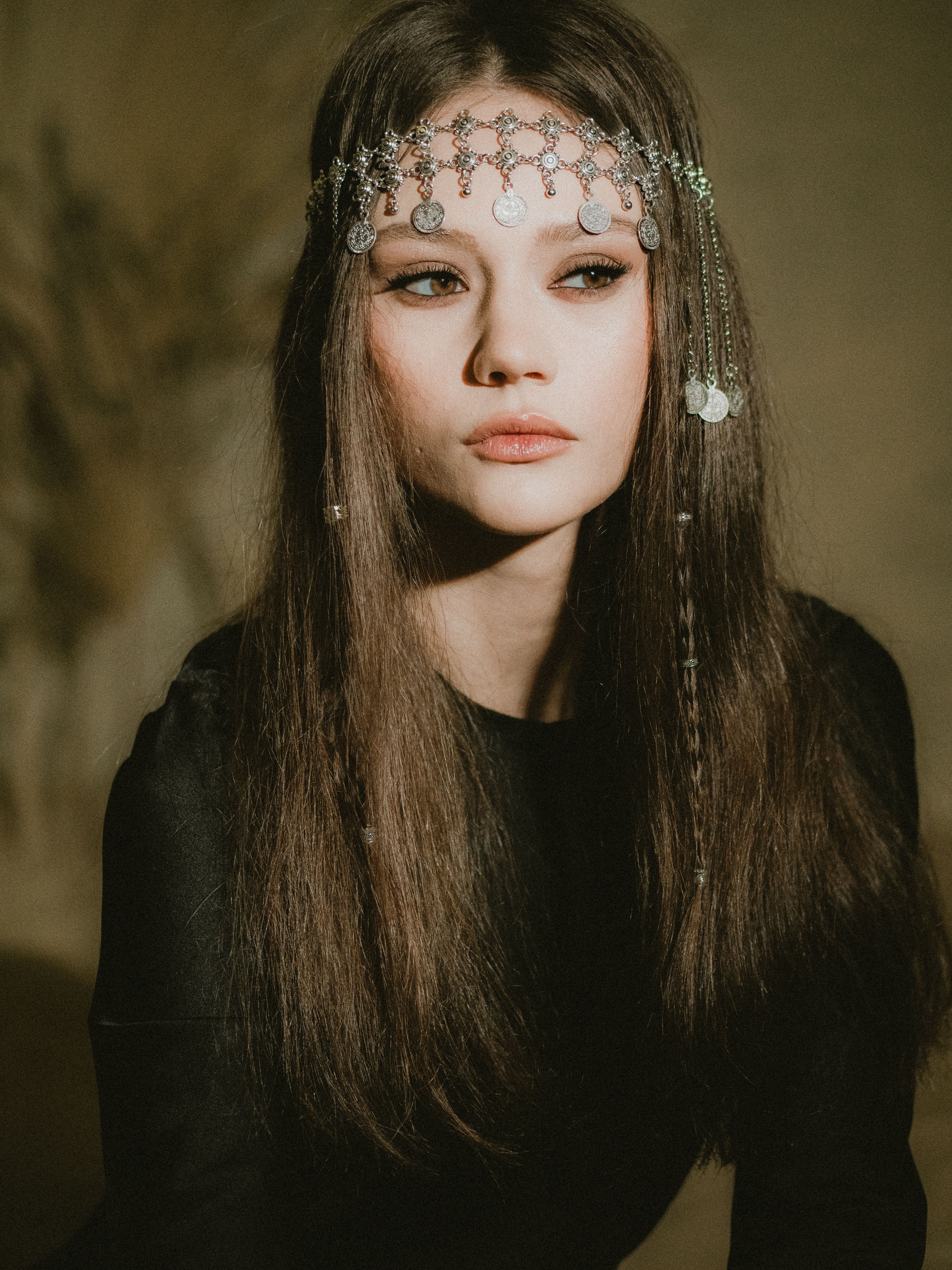 Captivating portrait of a woman wearing intricate silver headpiece and elegant black outfit.
