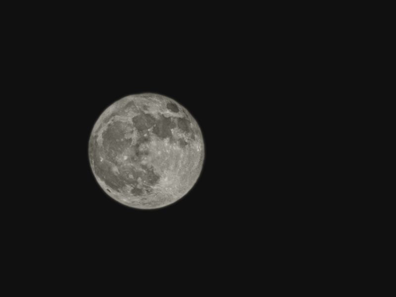 Stark full moon captured against a deep black night sky, showcasing lunar features.