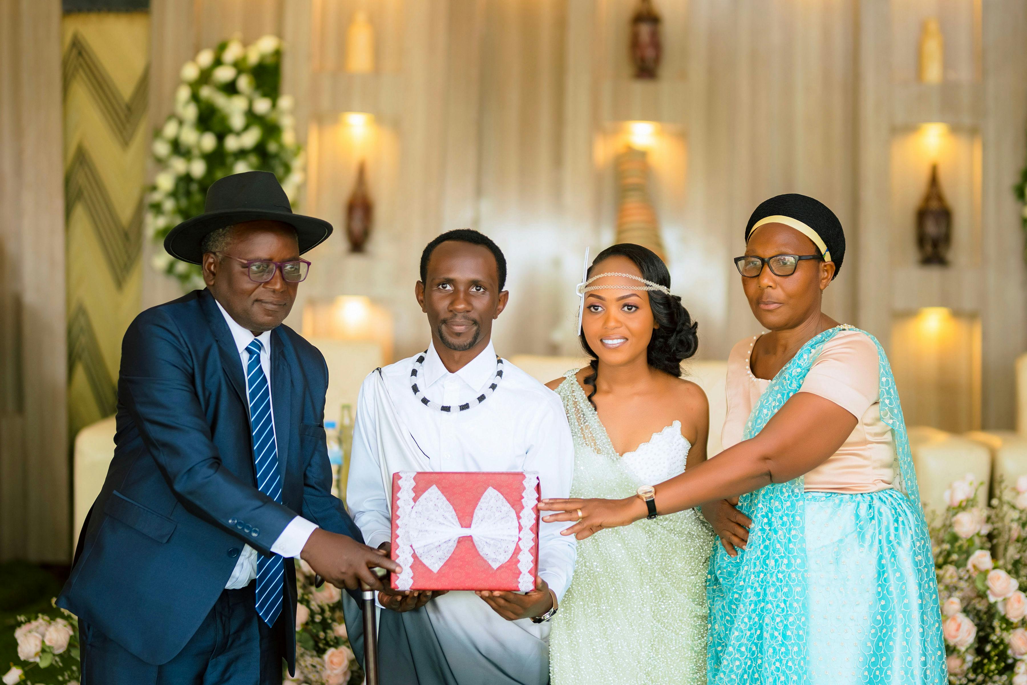 A joyful wedding celebration featuring the bride, groom, and family presenting a gift.