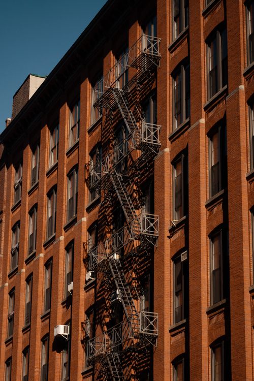 Free Urban red brick building with classic fire escape at sunset, showcasing architectural details. Stock Photo