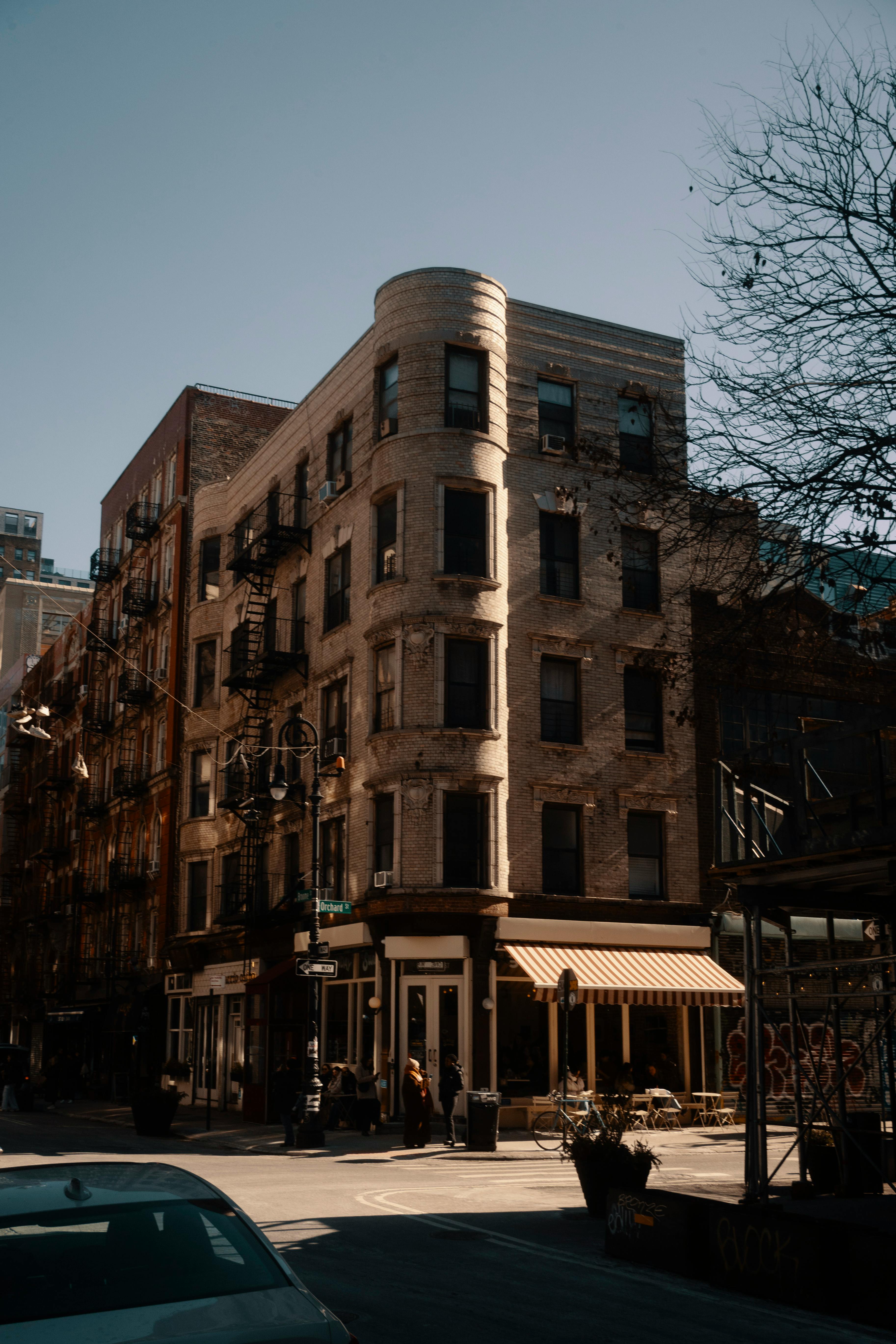 Free Sunlit street corner featuring classic brick building under a clear blue sky. Stock Photo