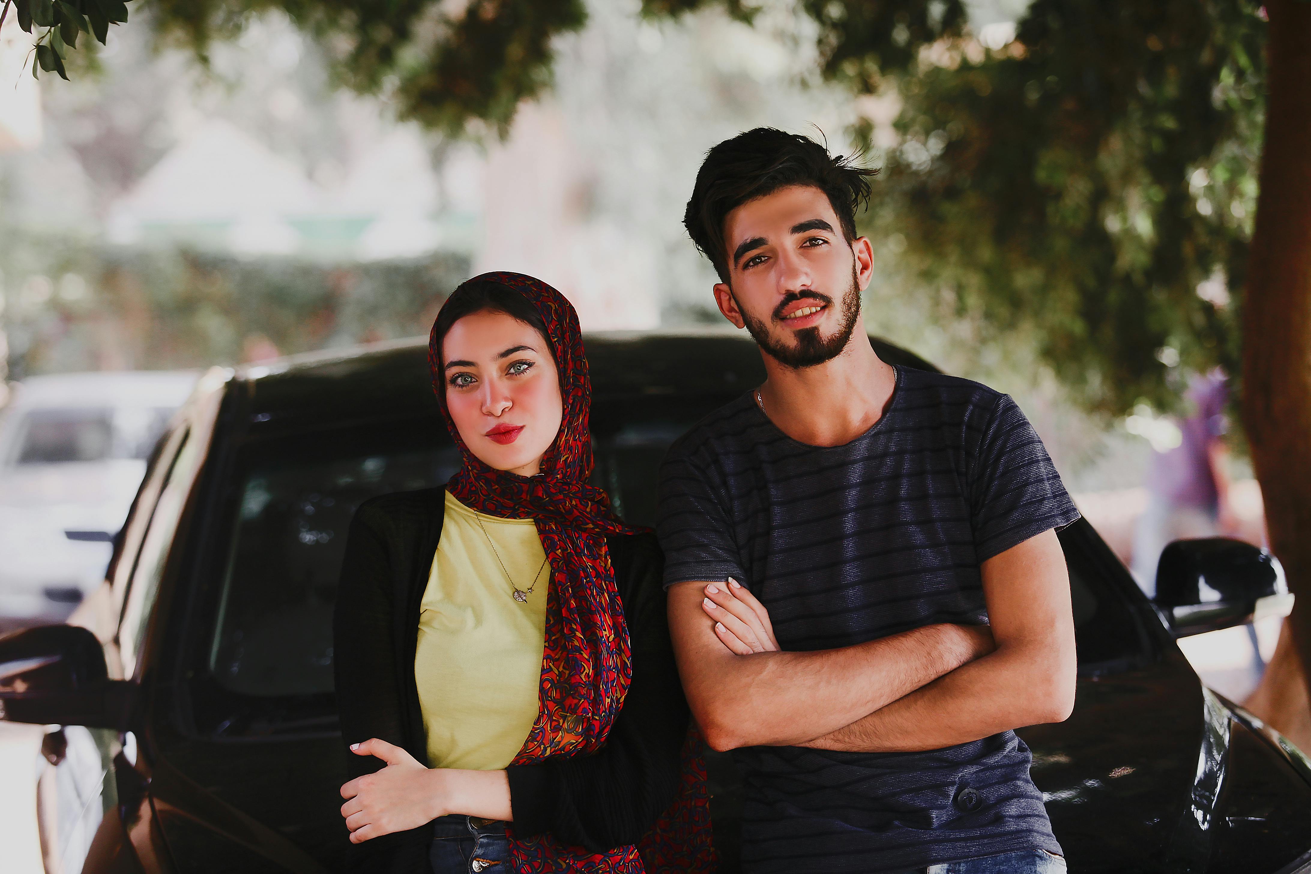 一对时髦的年轻男女在树下与汽车合影