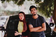 一对时髦的年轻男女在树下与汽车合影