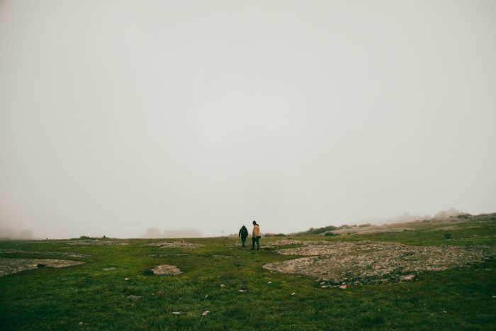 Two figures walking across foggy grassland — photo by Marcelo Mora on Pexels