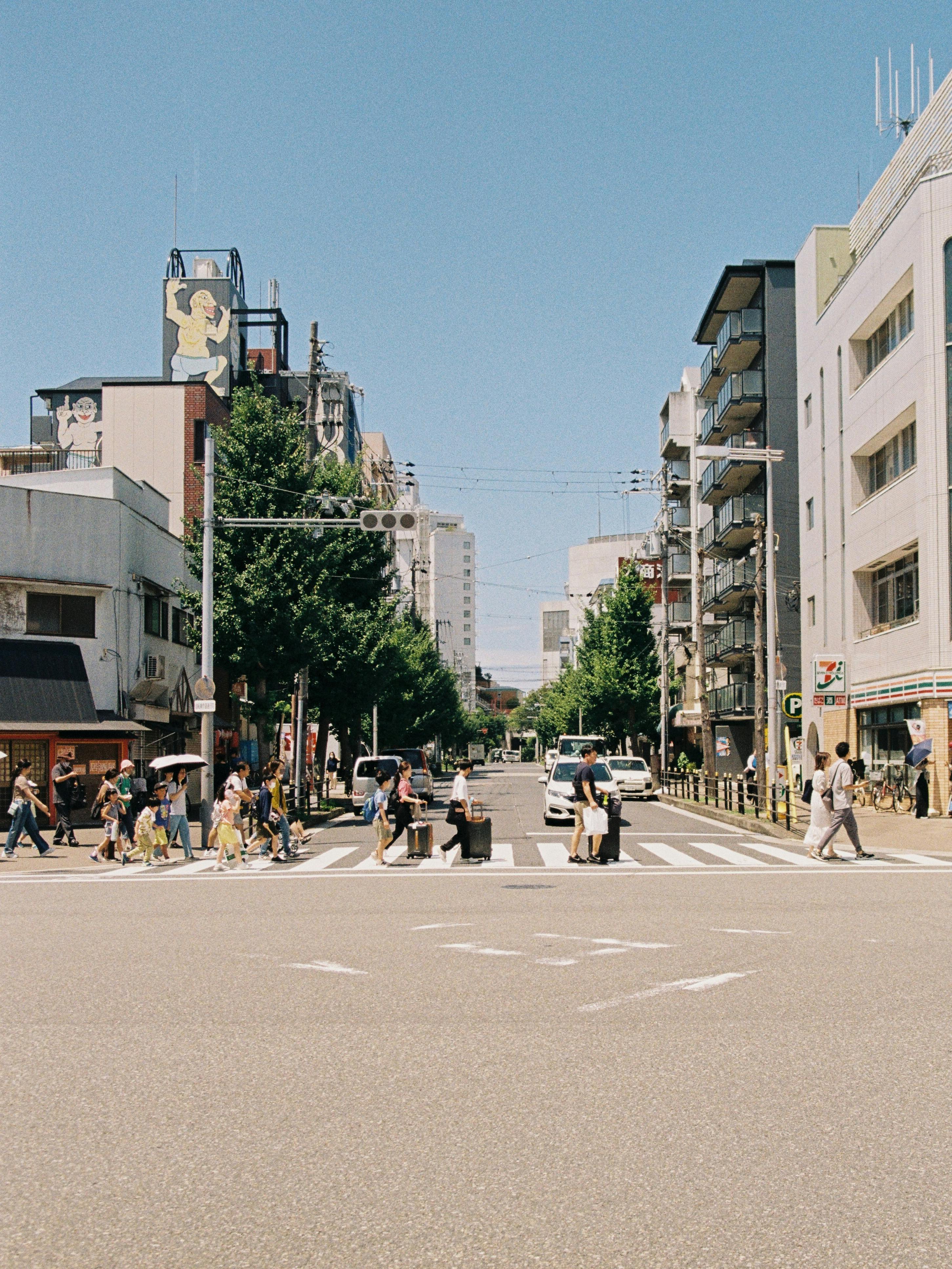 Pedestrians cross a vibrant city street under a clear blue sky.