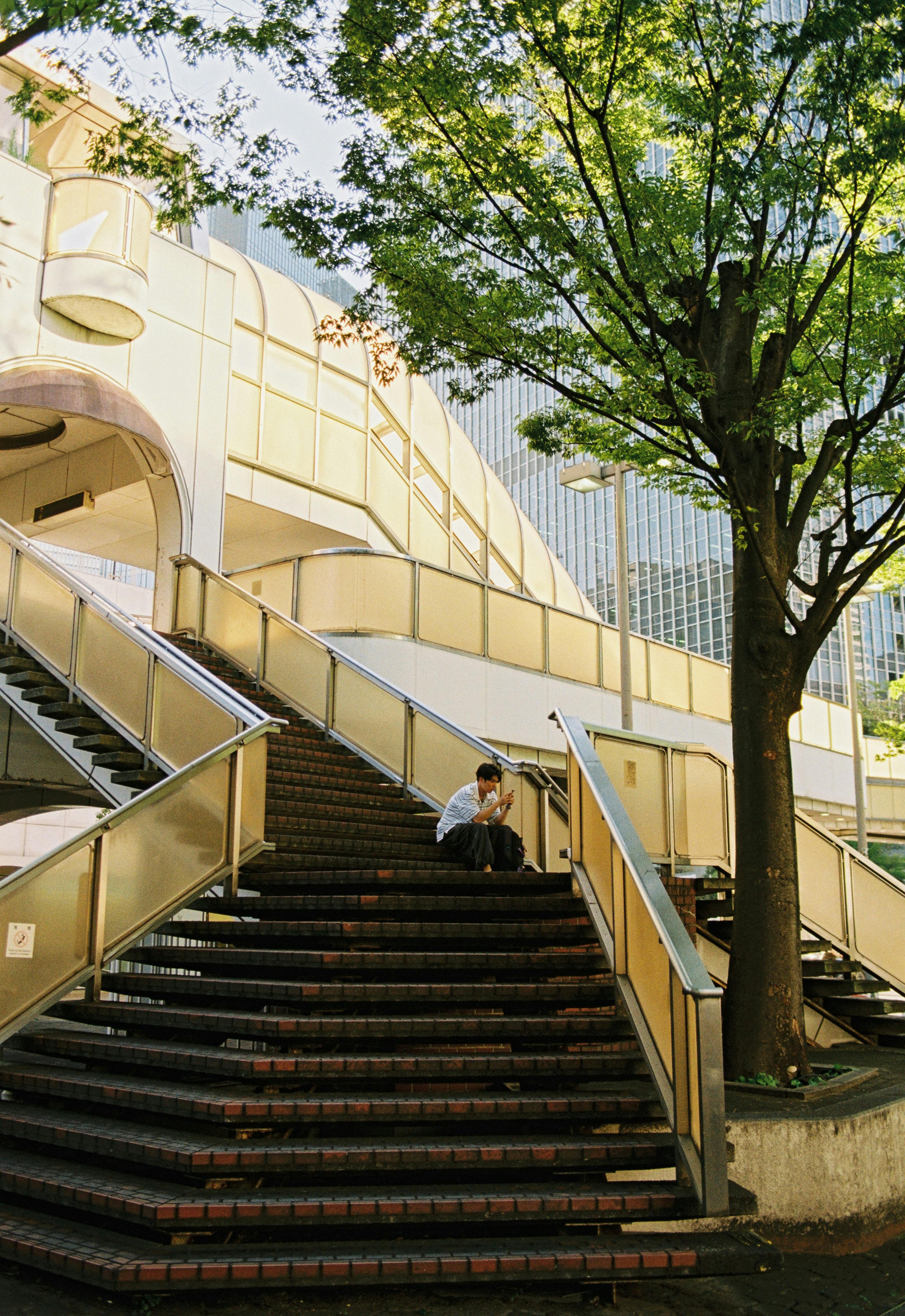 Man sitting on staircase in urban environment with modern architecture.