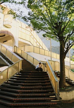 Man sitting on staircase in urban environment with modern architecture.