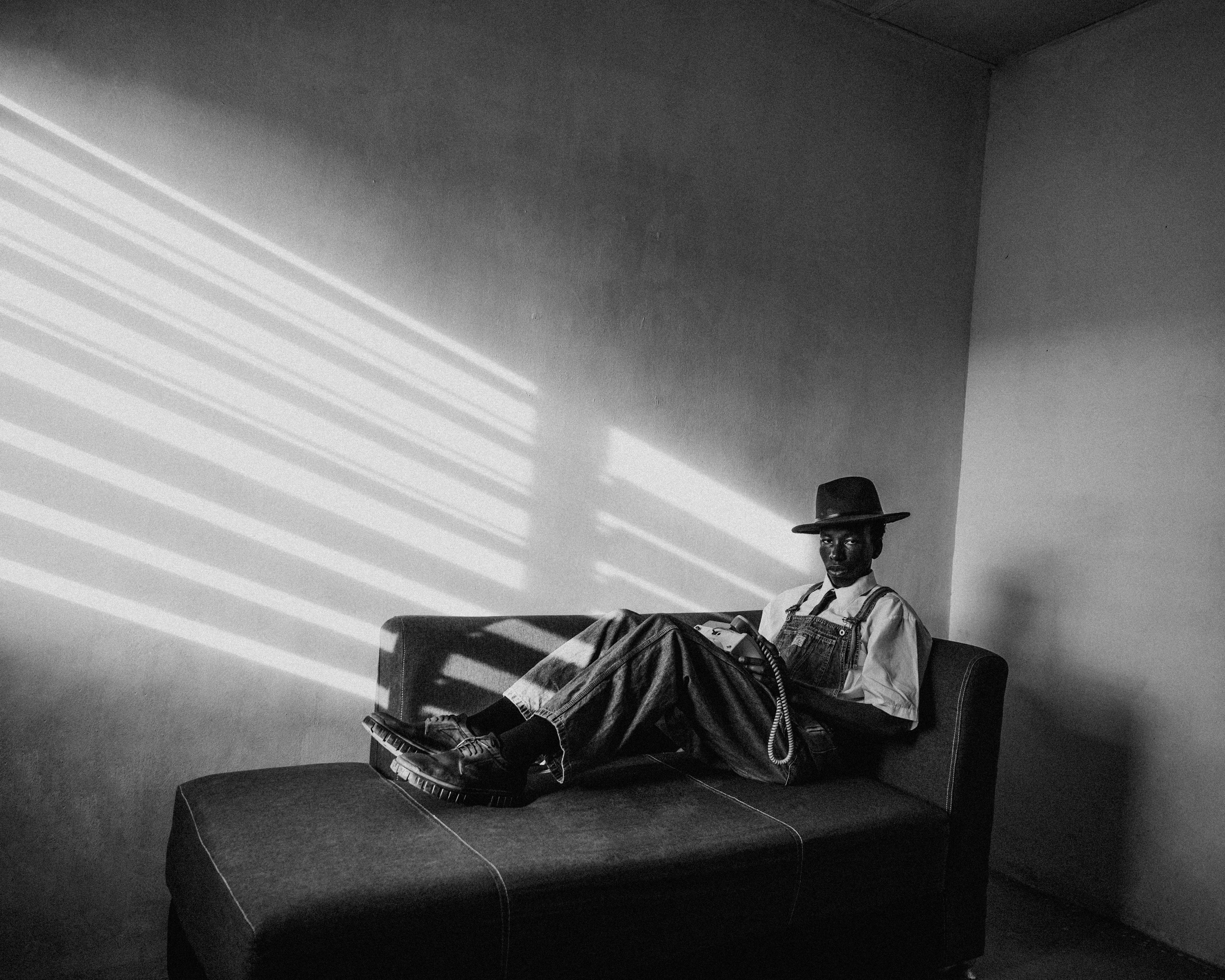 Black and white portrait of a man lounging in a sunlit room, evoking a moody and classic vibe.