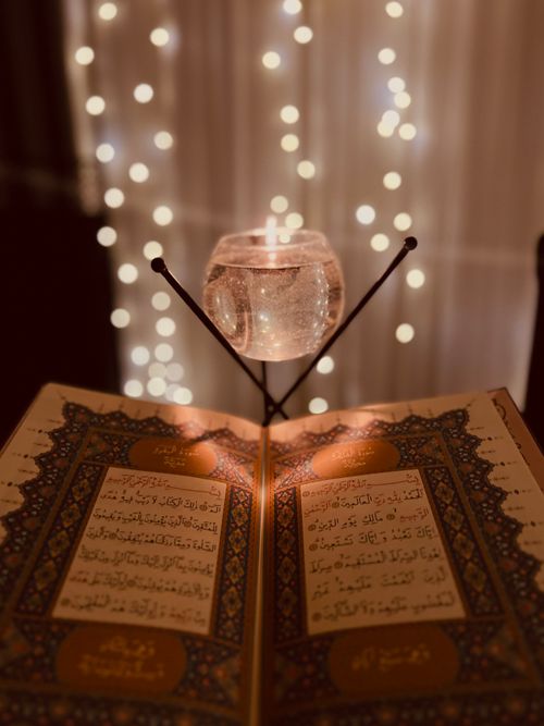Free A beautifully illuminated Quran with a candle in soft bokeh lighting, creating a serene and spiritual ambience. Stock Photo