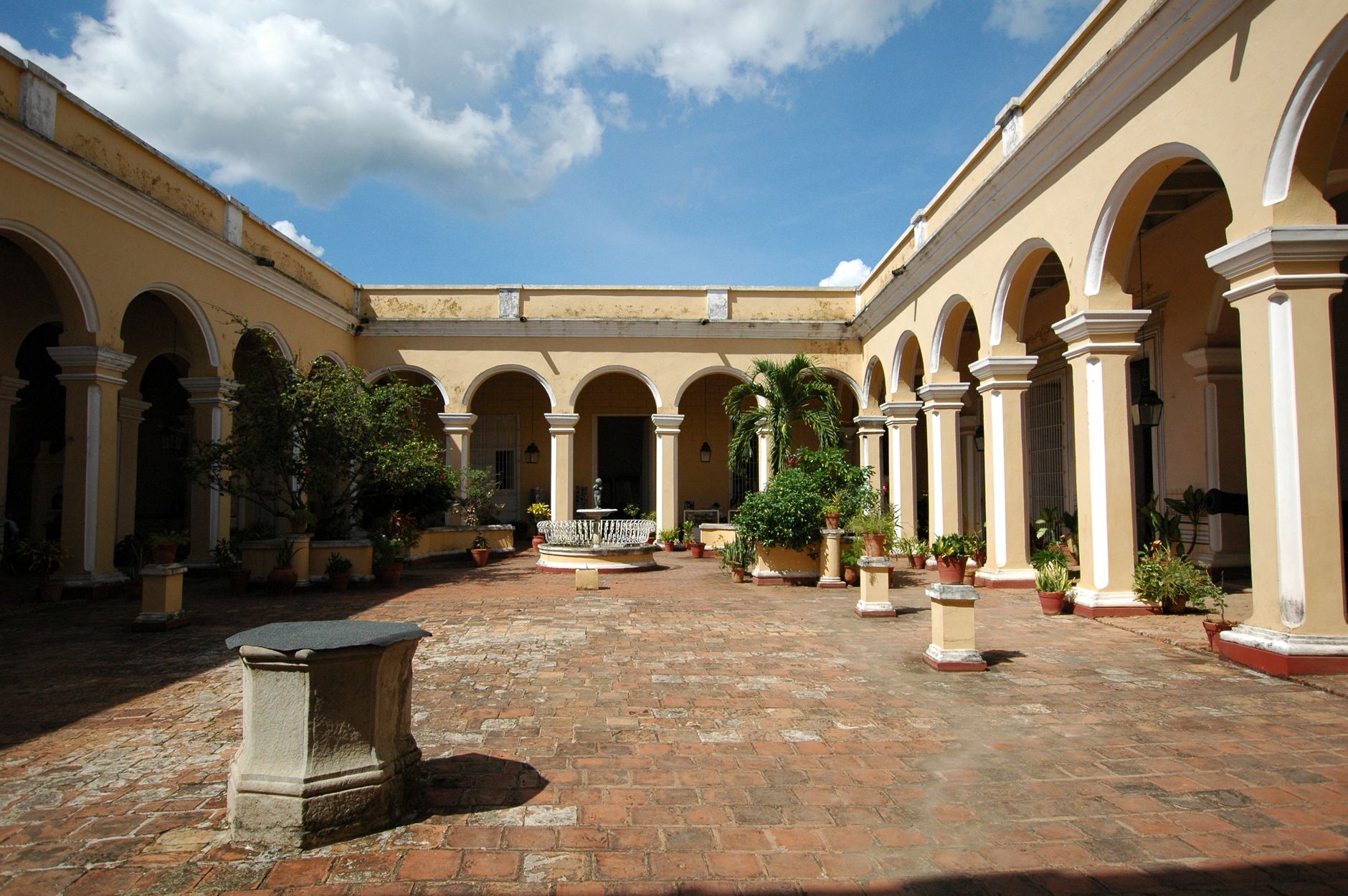 Scenic view of a colonial courtyard with arches and plants, showcasing historic Cuban architecture.
