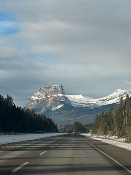 Snowy Castle Mountain view along a clear forest highway. Winter travel through Canadian Rockies.