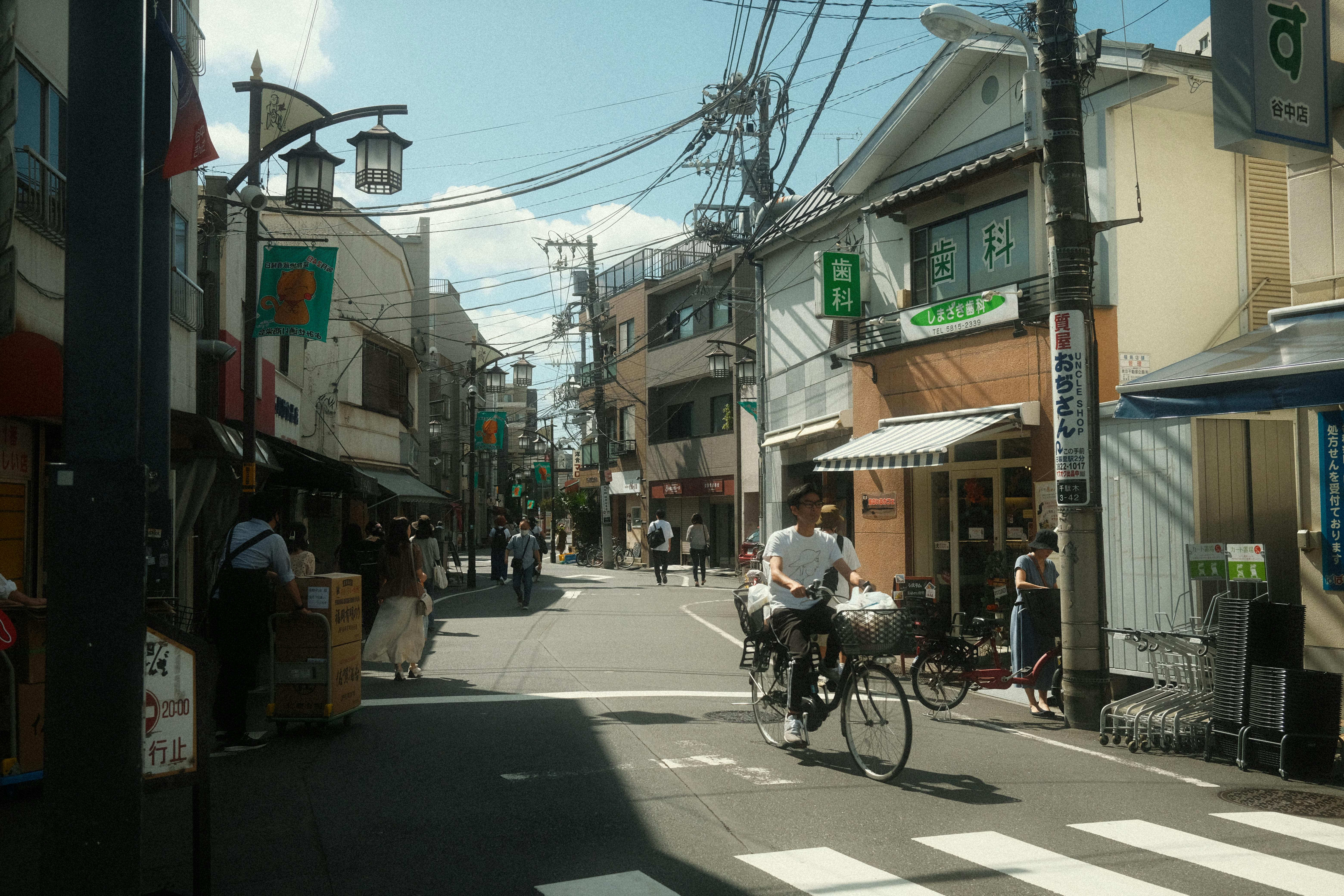 Busy street in Tokyo, Japan, showcasing daily life with bicycles and pedestrians under clear skies.
