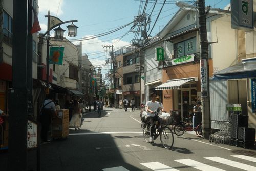 Free Busy street in Tokyo, Japan, showcasing daily life with bicycles and pedestrians under clear skies. Stock Photo