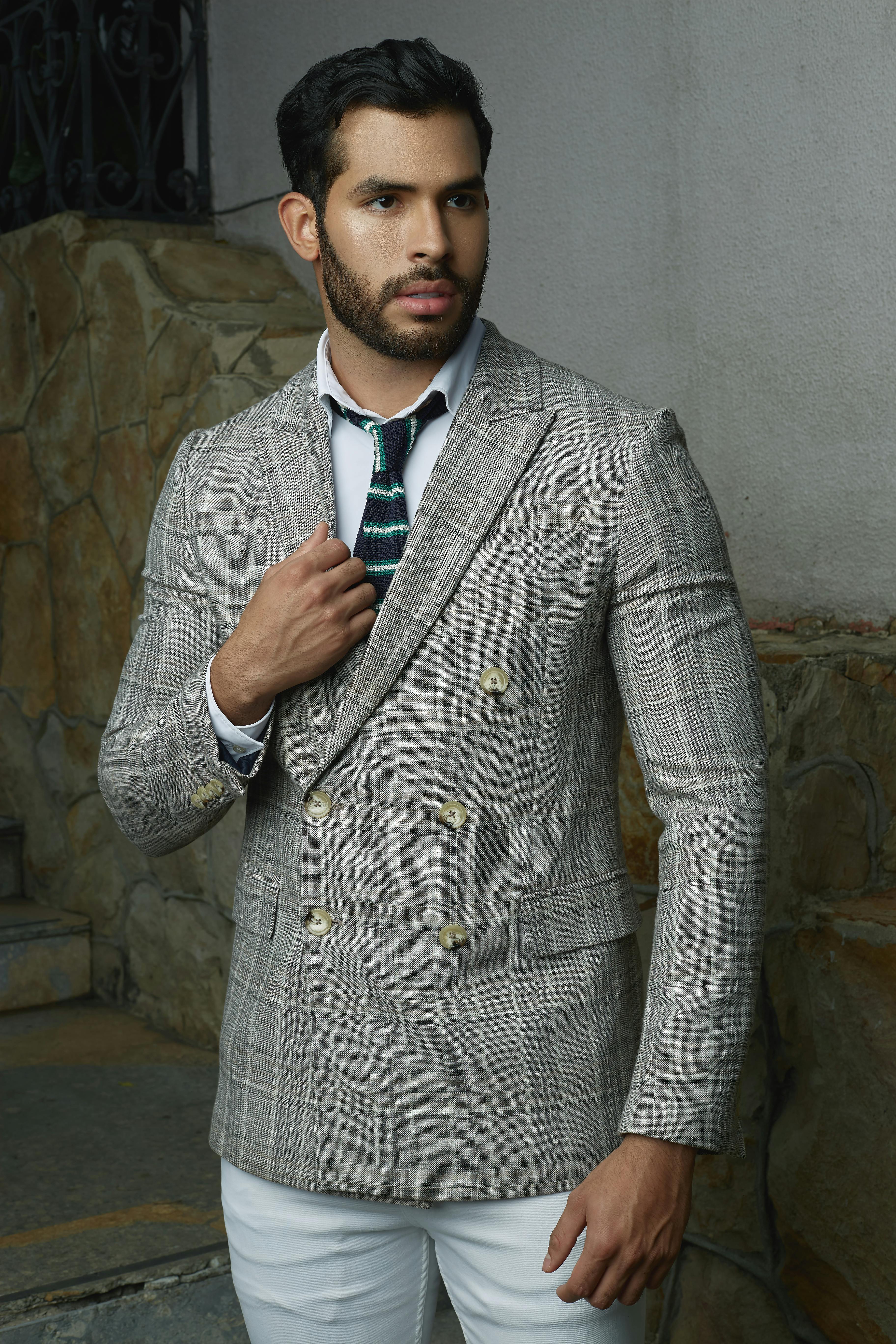Portrait of a stylish man dressed in a double-breasted suit, standing outdoors.
