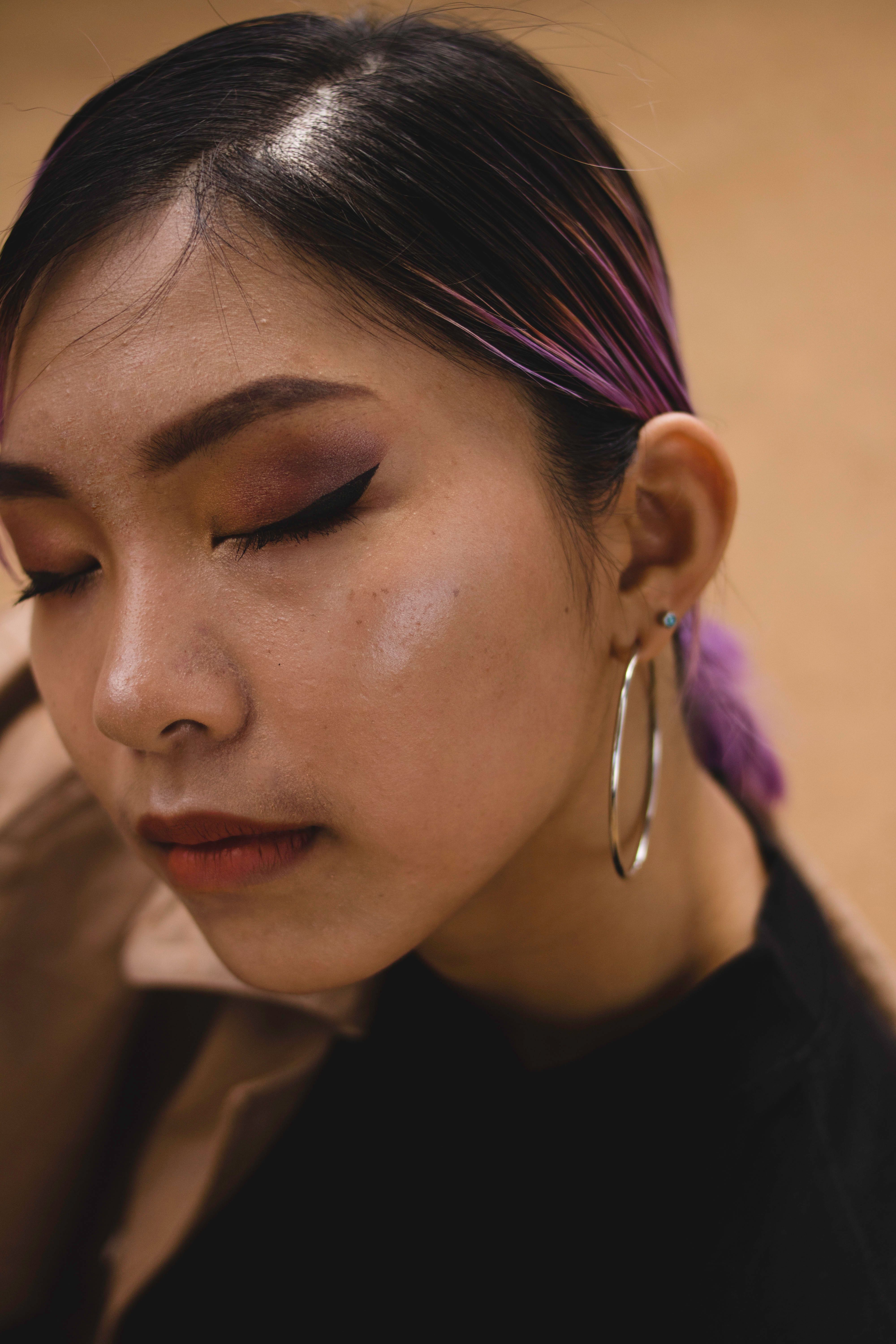 Elegant close-up portrait of a woman with striking eye makeup and hoop earrings.