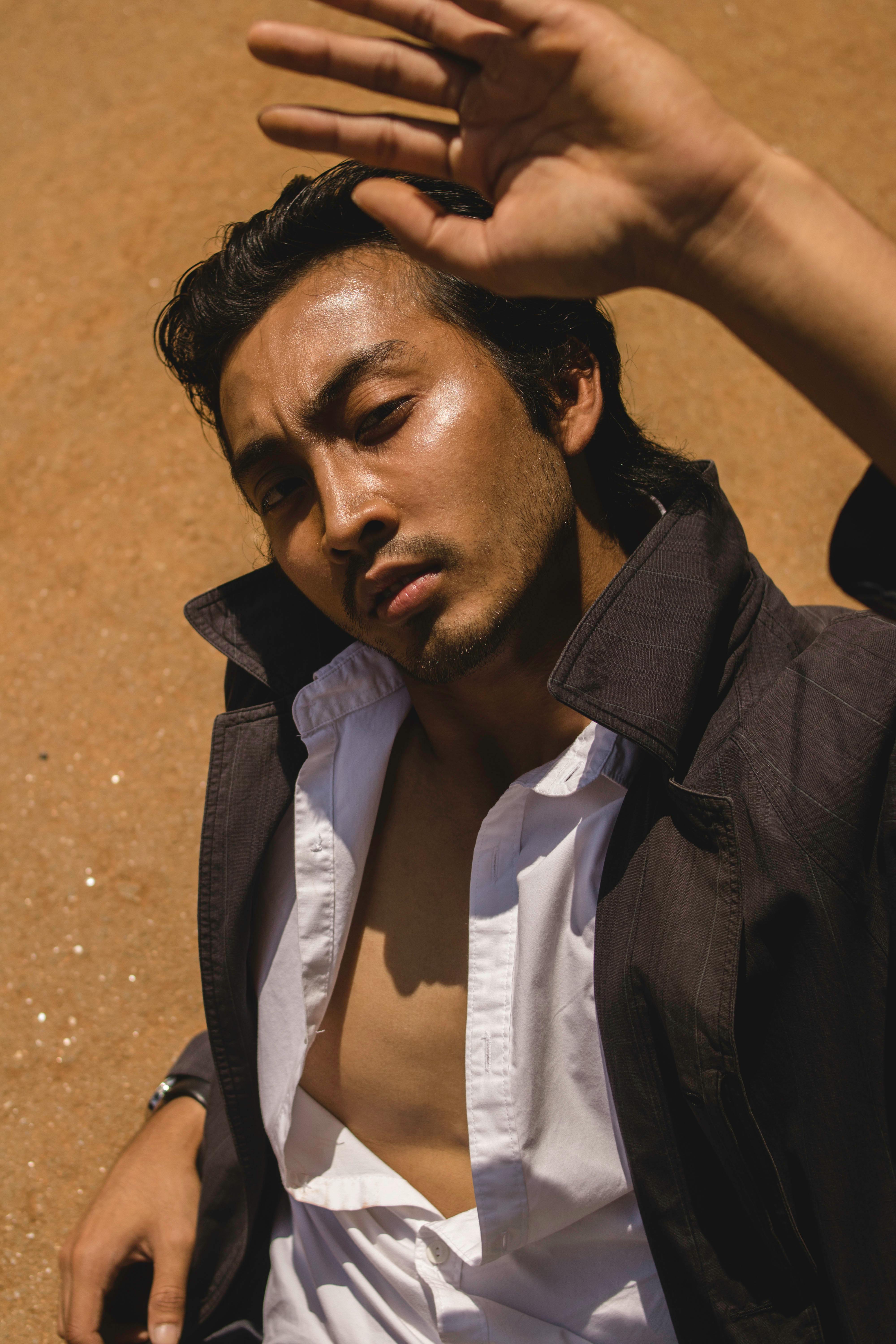 一个时髦的男人在户外摆姿势，用手遮挡阳光保护眼睛